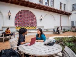 two women talking at an outdoor table on campus